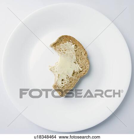 Picture - High angle view of brown bread with butter on a plate. Fotosearch
