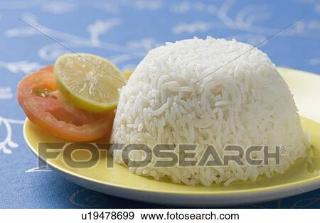 Stock Photo - Close-up of white rice in a plate with slices of lemon and tomato. Fotosearch