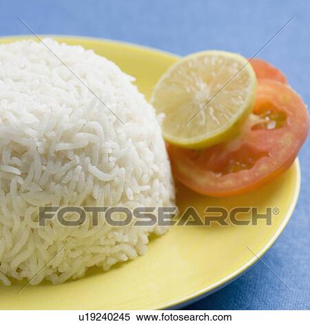 Stock Photography - Close-up of white rice in a plate with slices of lemon and tomato. Fotosearch