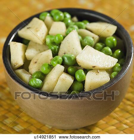 Stock Image - High angle view of a bowl of fried green peas and potatoes. Fotosearch