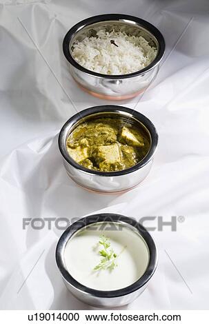 Stock Image - High angle view of three bowls of shahi paneer with curd and rice. Fotosearch