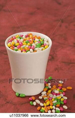Stock Photograph - Jellybeans assorted near a plastic glass. Fotosearch