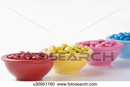Stock Image - Row of four bowls filled with candies. Fotosearch