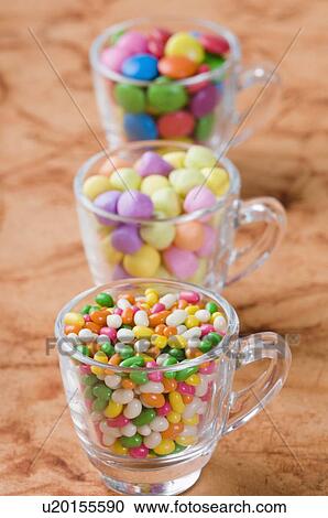 Stock Image - Row of three cups filled with jellybeans and candies. Fotosearch