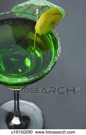 Stock Image - Close-up of a lemon slice and a drink umbrella on a glass of margarita. Fotosearch