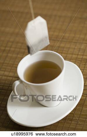 Stock Photograph - Close-up of a cup of herbal tea on a saucer with a teabag. Fotosearch