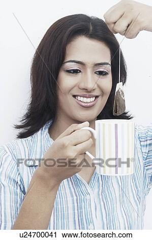 Close-up of a young woman dipping a teabag into a tea cup View Large Photo Image Stock Image - Close-up of a young woman dipping a teabag into a tea cup. Fotosearch