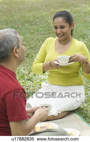 Stock Photography - Mid adult couple sitting together and drinking tea. Fotosearch
