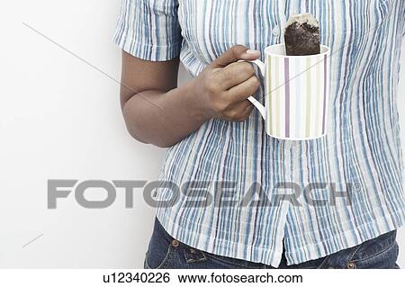 Mid section view of a woman dipping a teabag into a tea cup View Large Photo Image Stock Photograph - Mid section view of a woman dipping a teabag into a tea cup. Fotosearch