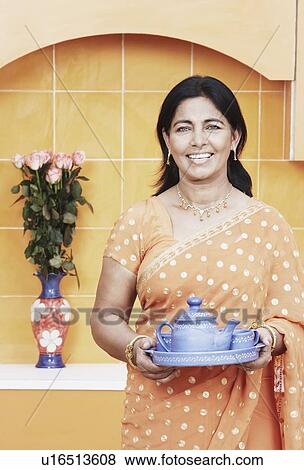 Portrait of a mature woman holding tea cups and a tea kettle on a tray View Large Photo Image Stock Photo - Portrait of a mature woman holding tea cups and a tea kettle on a tray. Fotosearch