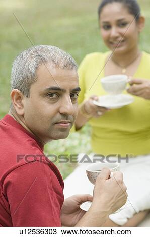 Portrait of a mid adult couple sitting together and drinking tea View Large Photo Image Stock Image - Portrait of a mid adult couple sitting together and drinking tea. Fotosearch