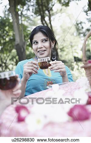 Stock Image - Young woman holding a cup of black tea. Fotosearch