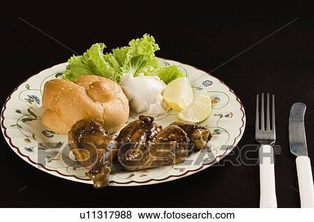 Stock Photo - Close-up of roast chicken with a bun in a plate. Fotosearch
