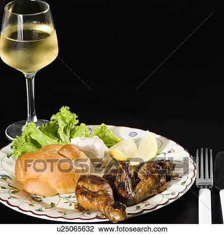 Stock Image - Close-up of roasted chicken and bun in a plate with a glass of wine. Fotosearch