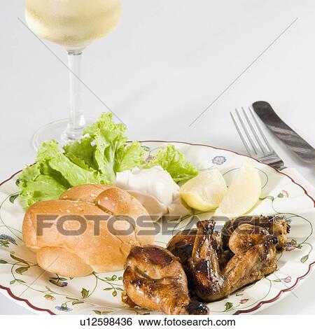 Stock Photograph - Close-up of roasted chicken and bun in a plate with a glass of wine. Fotosearch