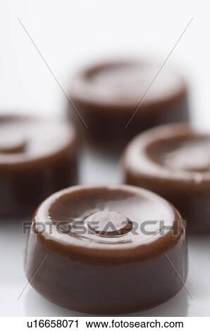 Stock Image - Close-up of four brown candies. Fotosearch