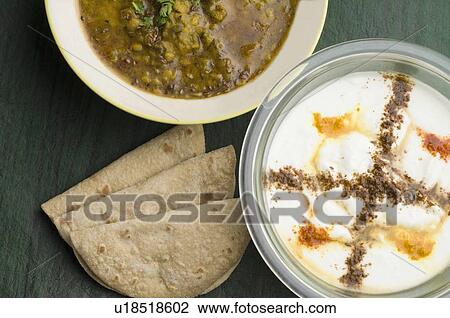 Stock Image - Close-up of three chapattis with chickpea curry and rayta. Fotosearch