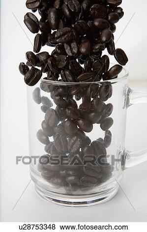 Stock Photo - Coffee beans pour into clear coffee cup. Fotosearch