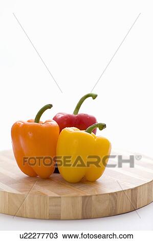 Stock Image - Yellow, orange and red peppers on butcher block cutting board. Fotosearch