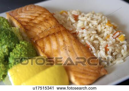 Stock Image - Dinner plate of salmon with rice and broccoli garnished with lemon wedges, Canada, Ontario. Fotosearch