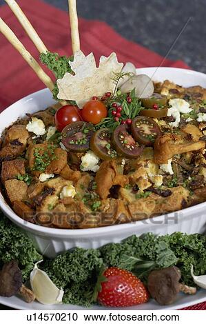 Stock Image - Egg soufflé with wild mushrooms and goat cheese garnished with black cherry tomatoes, breadsticks, kale and strawberries. Fotosearch