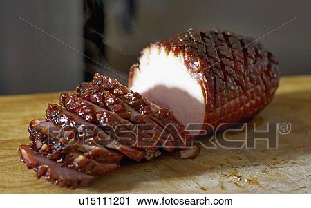 Stock Image - Oven roasted ham sliced up on cutting board. Fotosearch