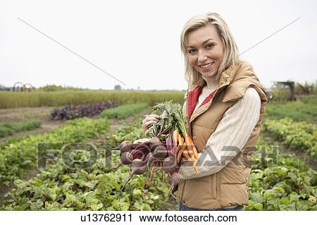 Stock Image - Woman with a bundle of fresh organic vegetables, British Columbia, Canada. Fotosearch