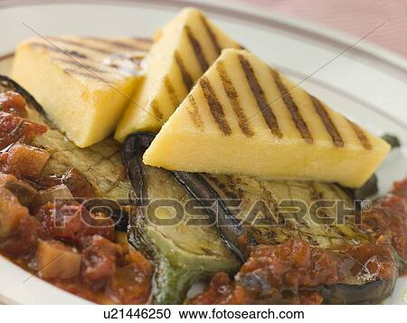 Stock Image - Chargrilled Polenta Cakes with Fried Egg Plant Tomato and Egg Plant Sauce. Fotosearch