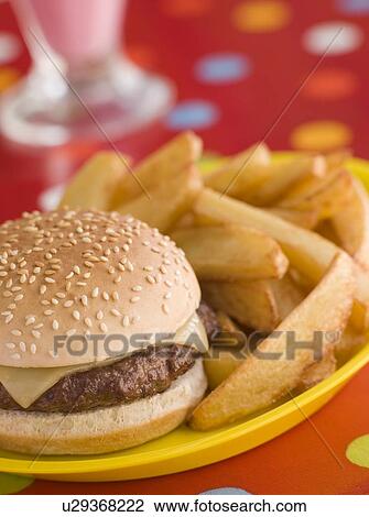 Stock Image - Cheeseburger in a Sesame Seed Bun with Chunky Chips. Fotosearch