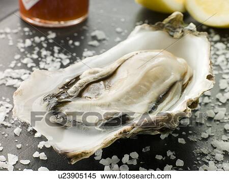 Stock Photography - Opened Rock Oyster with Hot Chilli Sauce Lemon and Sea Salt. Fotosearch