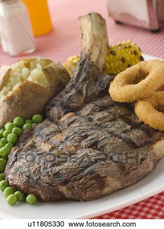 Ribeye Steak on the bone with Baked Potato Peas Onion Rings and Corn View Large Photo Image Stock Image - Ribeye Steak on the bone with Baked Potato Peas Onion Rings and Corn. Fotosearch