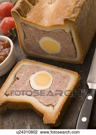 Stock Image - Pork and Egg Gala Pie with Tomato Chutney. Fotosearch