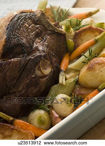 Stock Image - Roast Leg of Spring Lamb With Roast Potatoes and Vegetables. Fotosearch