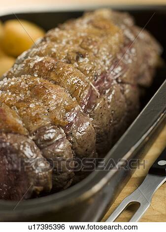 Stock Photograph - Roast Topside of British Beef in a Tray with Roast Potatoes. Fotosearch