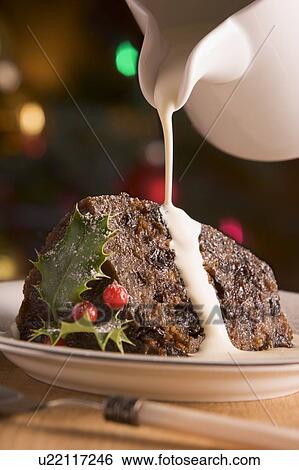 Stock Photograph - Portion of Christmas Pudding with Pouring Cream. Fotosearch
