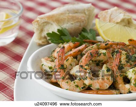 Stock Photograph - Dish of Garlic Buttered Tiger Prawns with Rustic Bread. Fotosearch