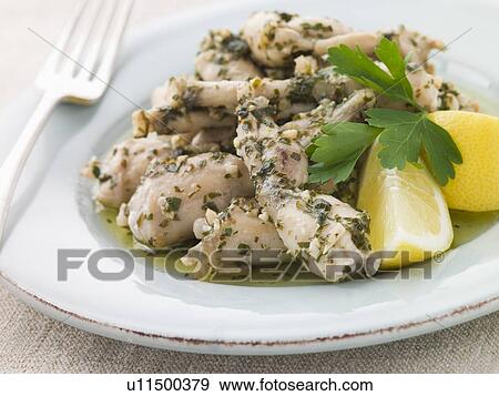 Stock Photo - Frogs Legs Fried in Garlic and Herb Butter with Lemon. Fotosearch