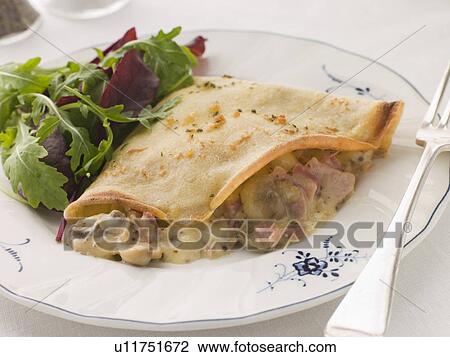Stock Image - Savoury Pancake filled with Ham Cheese and Mushrooms with dressed salad. Fotosearch