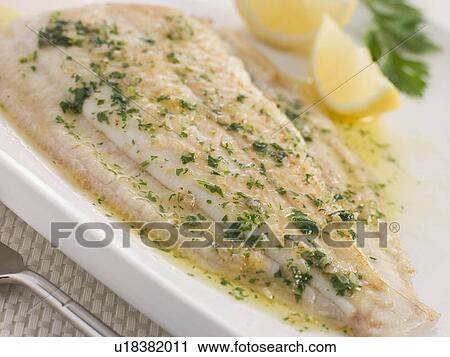 Stock Image - Whole Lemon Sole Meuniere with Lemon and Parsley Garnish. Fotosearch