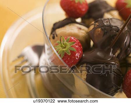 Stock Image - Chocolate Profiteroles with Strawberries and Chocolate Sauce. Fotosearch