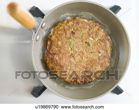 Stock Image - Savoury Pancake Cooking in a Japanese Frying Pan. Fotosearch
