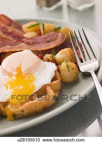Stock Image - Waffles with Bacon Fried Potatoes and a Broken fried Egg. Fotosearch