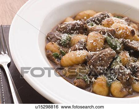 Stock Photograph - Oxtail Braised in Red Wine with Basil Gnocchi and Parmesan Cheese. Fotosearch