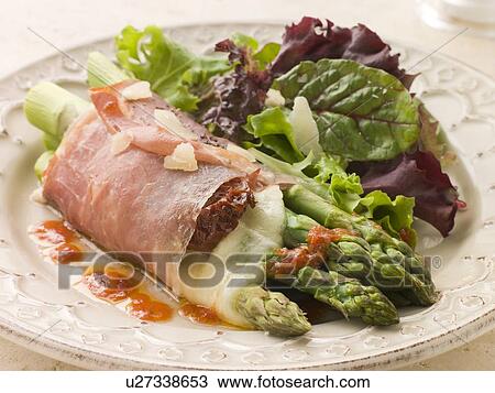 Stock Image - Roasted Asparagus spears with Mozzarella Cheese and Sun Dried Tomatoes wrapped in Prosciutto. Fotosearch