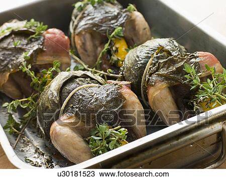 Stock Image - Quails Roasted in Vine Leaves with Lemon and Thyme. Fotosearch