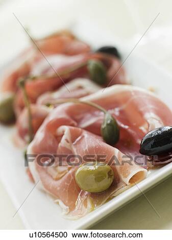 Stock Image - Serano Ham Olives and Caper Berries. Fotosearch