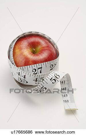 Stock Photograph - Close-up of an apple twisted by a tape measure. Fotosearch