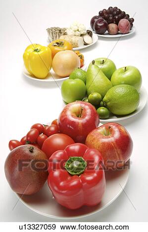 Stock Photo - Different kinds of fruits and vegetables on the plates, close-up. Fotosearch
