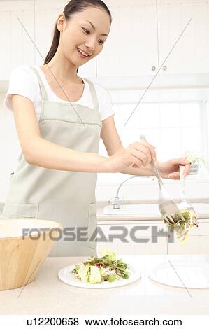 Stock Photo - Japanese woman serving salad in dish. Fotosearch