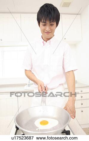 Man making a fried egg View Large Photo Image Stock Photo - Man making a fried egg. Fotosearch